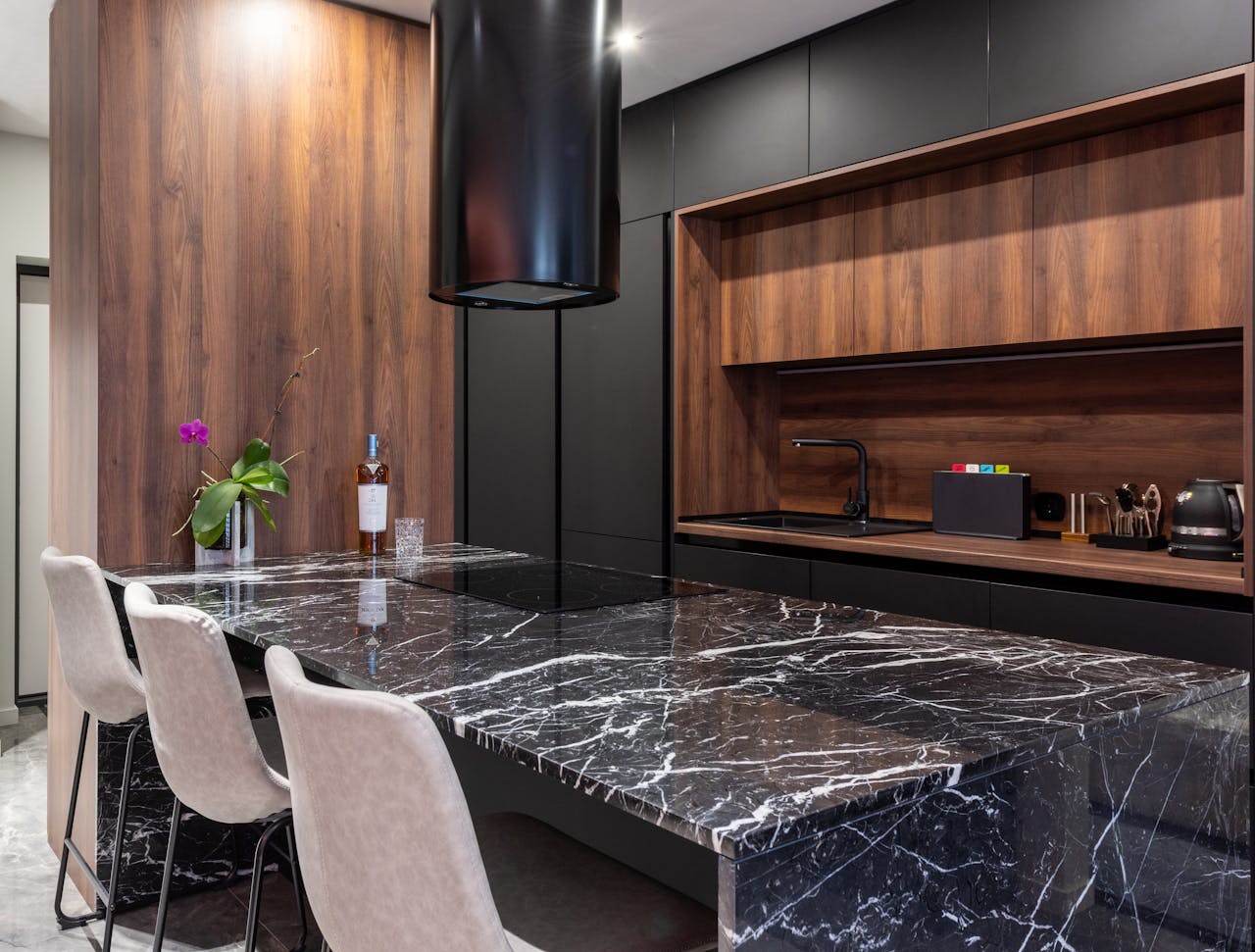 about-us Sleek modern kitchen featuring a black marble countertop, wooden cabinets, and elegant lighting.